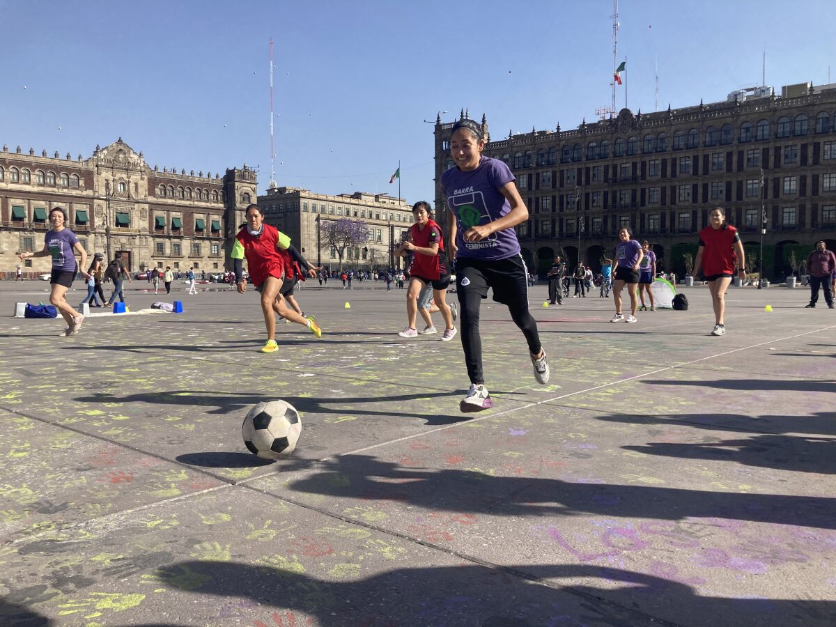 Women play soccer in a big plaza.