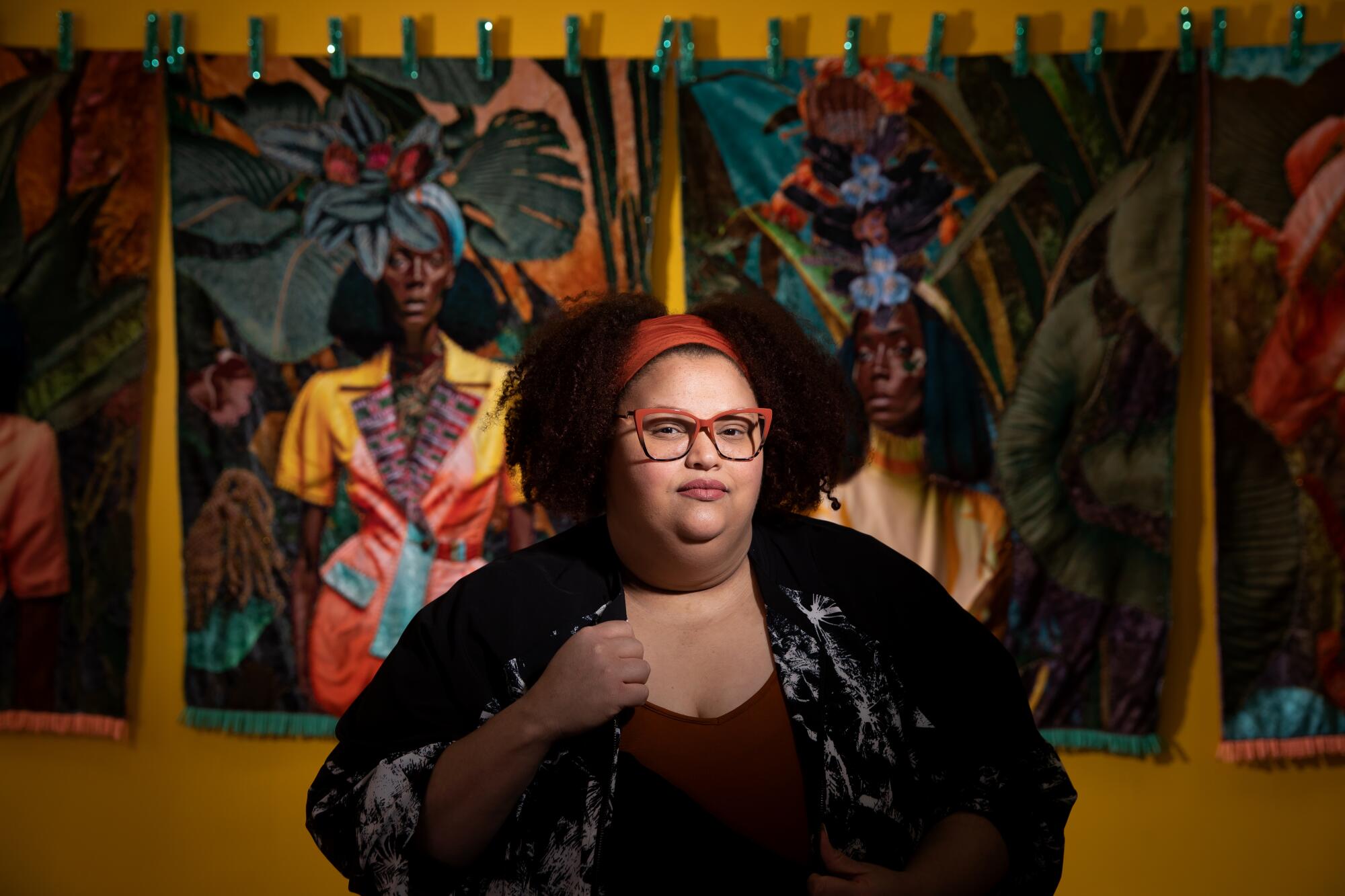 a woman stands in front of tapestries hanging on a wall