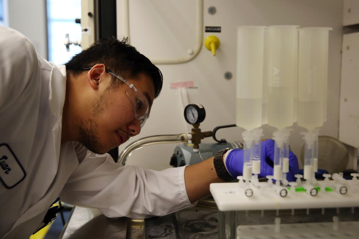 Twan Nguyen examines a machine testing water for chemicals at the Orange County Water District.