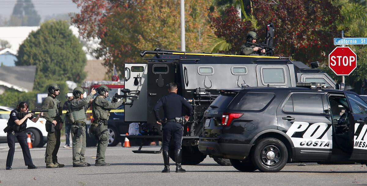  Costa Mesa police officers stand at the ready as a man gives himself up after an hours-long standoff on Wednesday morning.