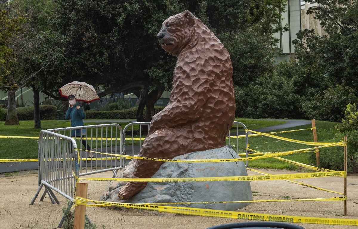 A statue of a prehistoric short-faced bear is surrounded by caution tape in the park at La Brea Tar Pits in Los Angeles.