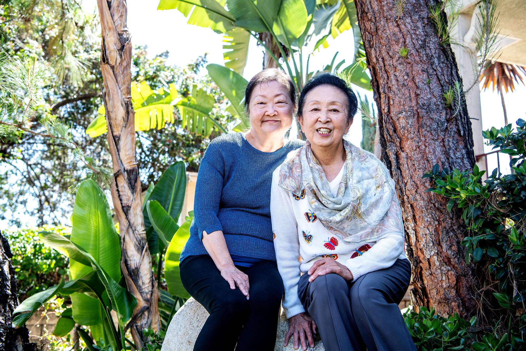 Becky Applegate and Takako Osumi sit next to trees.