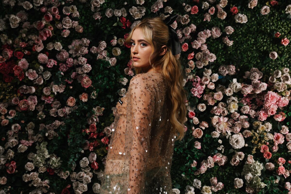  Kathryn Newton poses with flowers behind her