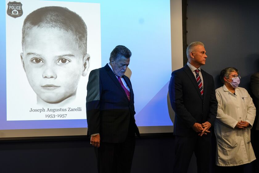 William C. Fleisher, with the Vidocq Society, center, Philadelphia Police Captain Jason Smith, and Dr. Constance DiAngelo, Philadelphia Chief Medical Examiner, listen during during a news conference in Philadelphia, Thursday, Dec. 8, 2022. Nearly 66 years after the battered body of a young boy was found stuffed inside a cardboard box, Philadelphia police have revealed the identity of the victim in the city's most notorious cold case. Police identified the boy as Joseph Augustus Zarelli. (AP Photo/Matt Rourke)