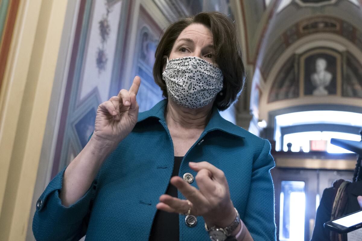 A masked woman gestures while speaking.