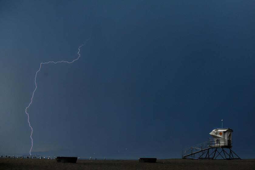 Huntington Beach, CA. October 4, 2021: A lightning bolt strikes the ocean near a lifeguard tower at Bolsa Chica State Beach as a storm passes through on Monday. (Wally Skalij/Los Angeles Times)