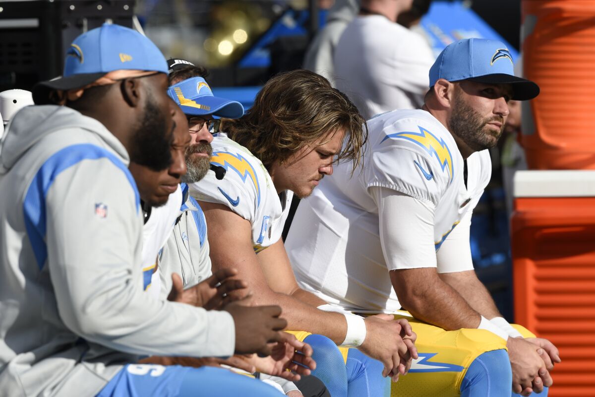 Los Angeles Chargers quarterbacks Justin Herbert, center, and Chase Daniel, right, sit on the bench Sunday.