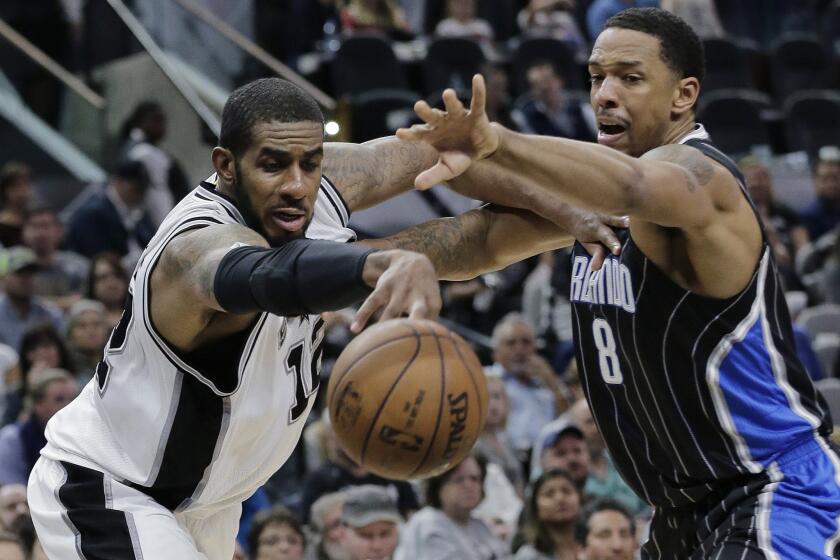 Spurs forward LaMarcus Aldridge (12) and Magic forward Channing Frye (8) reach for a loose ball during the second half.