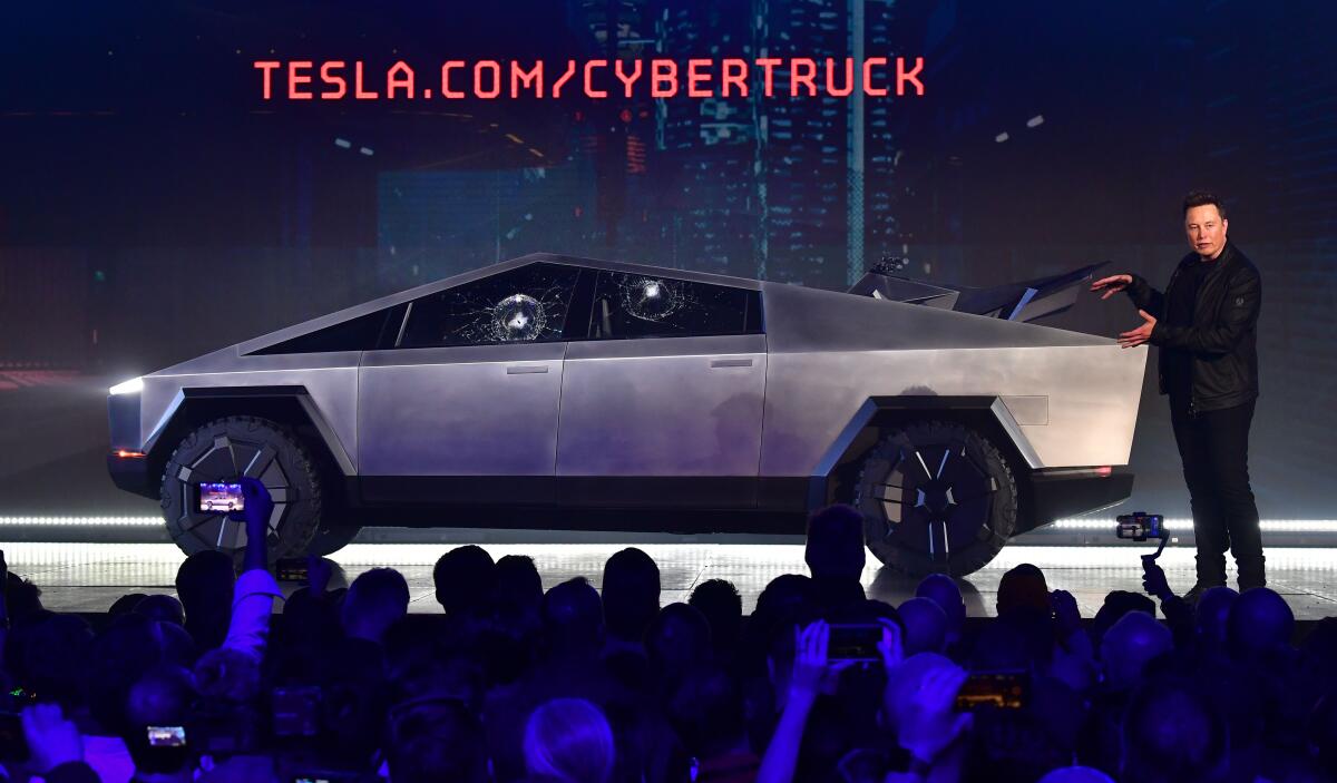 Tesla Chief Executive Elon Musk gesturing at a Tesla Cybertruck on a stage
