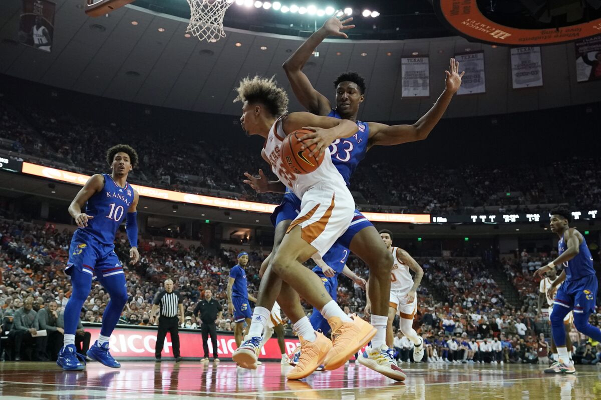 Texas forward Tre Mitchell, front center, drives around Kansas forward David McCormack (33)during the second half of an NCAA college basketball game, Monday, Feb. 7, 2022, in Austin, Texas. (AP Photo/Eric Gay)