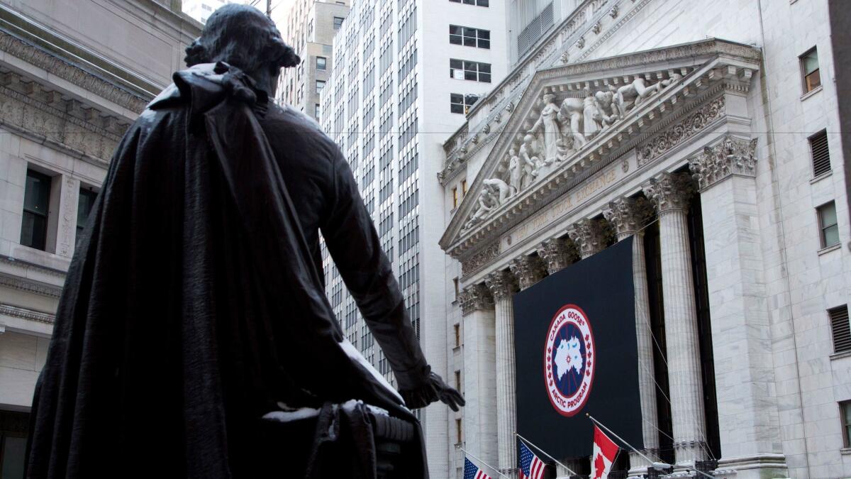 A statue of George Washington overlooks the New York Stock Exchange, which bears a banner for down-jacket maker Canada Goose.