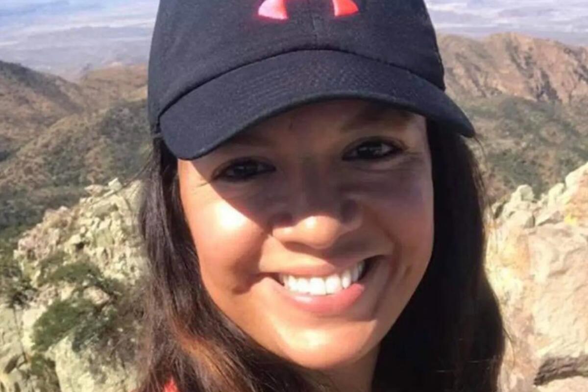 A closeup of a woman in a baseball cap, with mountains in the background