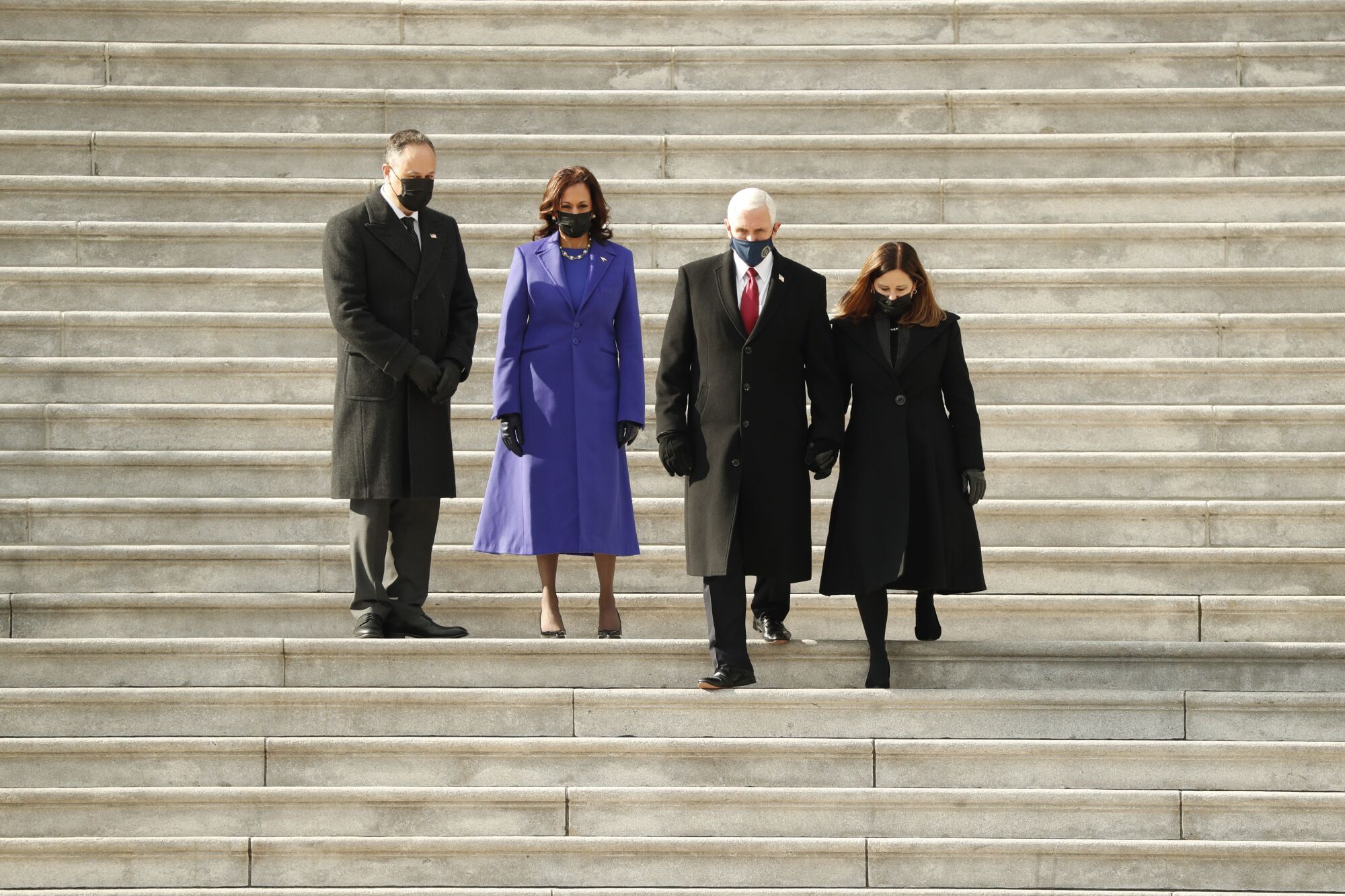 Kamala Harris and Doug Emhoff watch Mike Pence and his wife, Karen Pence, walk down steps.