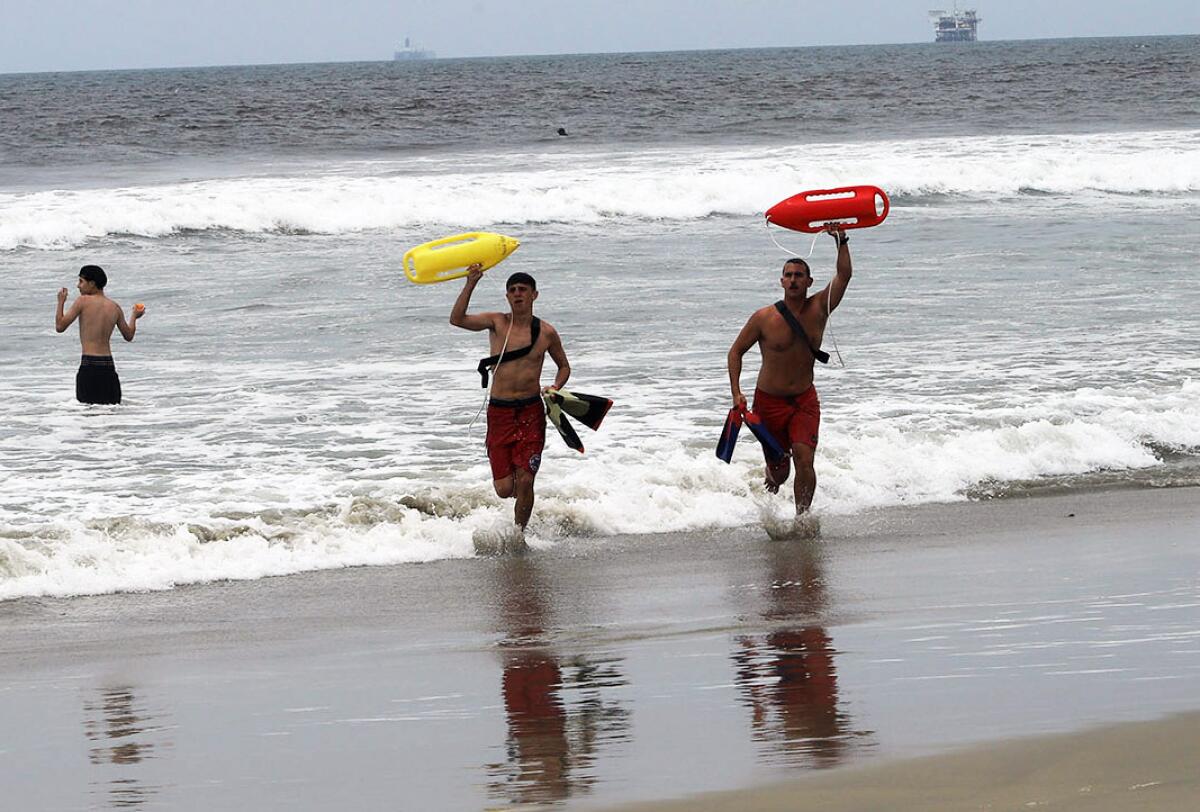 Jamie Bryson, left, a junior lifeguard visiting from New Zealand, left, and Huntington Beach Lifeguard Trevor Savage.