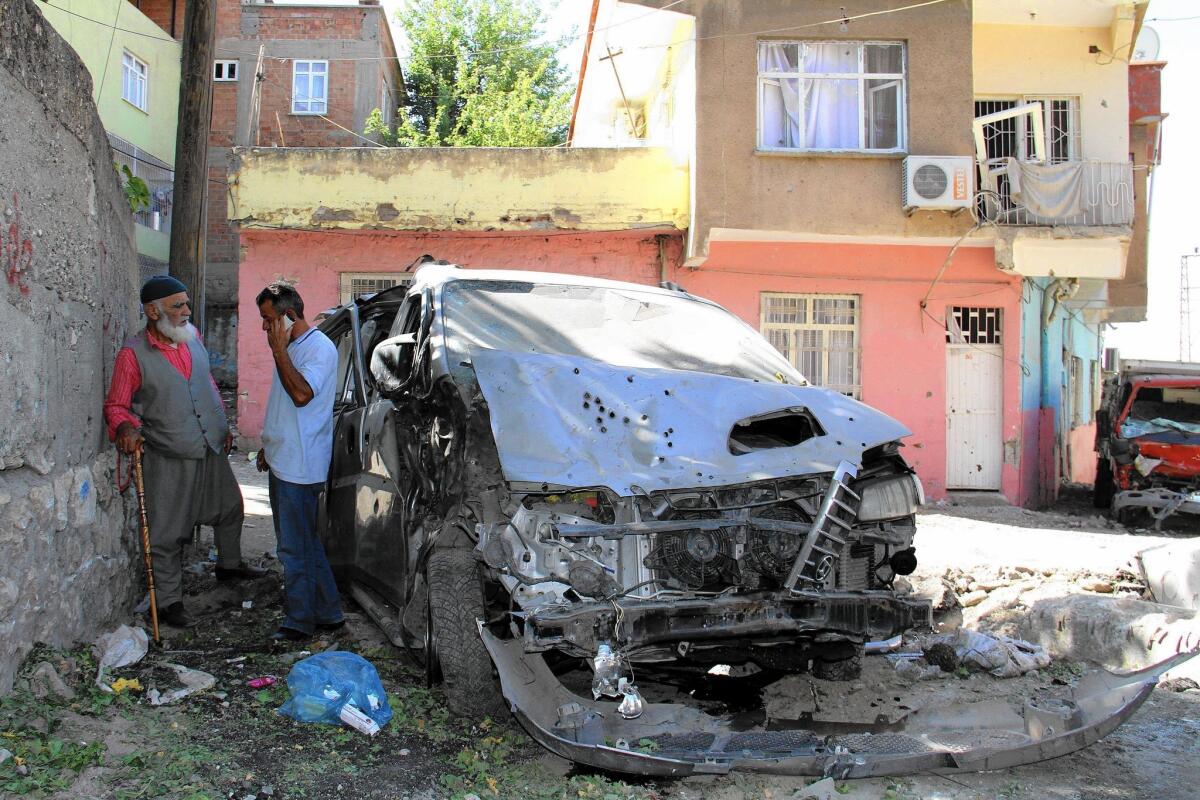 People stand near a destroyed car in Diyarbakir, Turkey, after clashes between the army and Kurdish rebels.