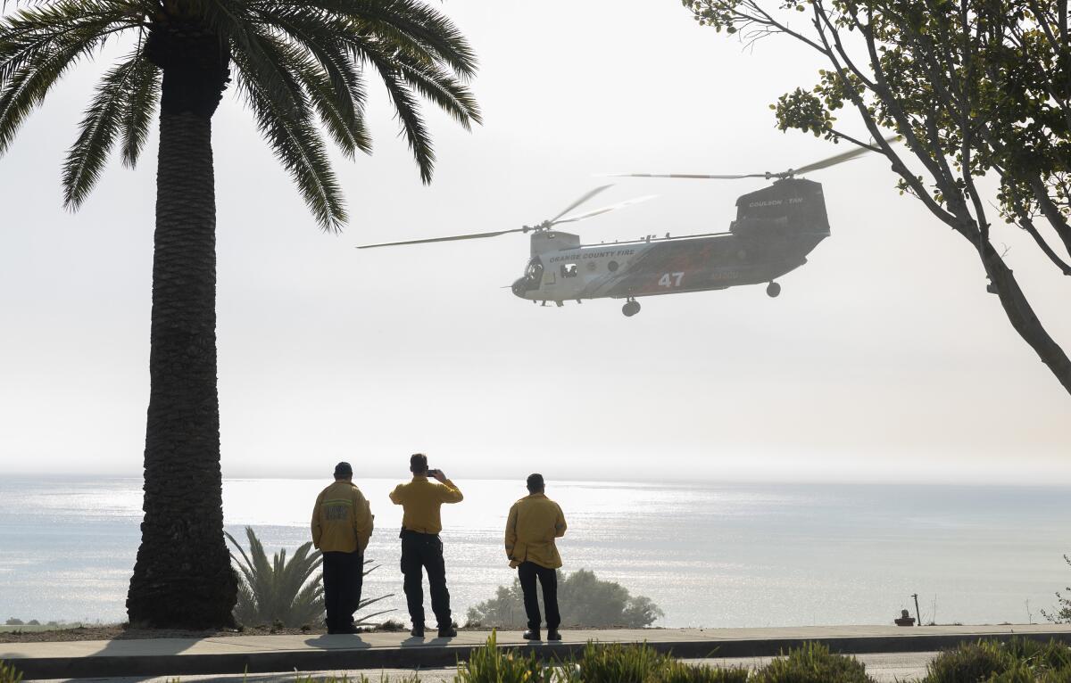 A fire helicopter lifts off after picking up water from a pond at Pepperdine University
