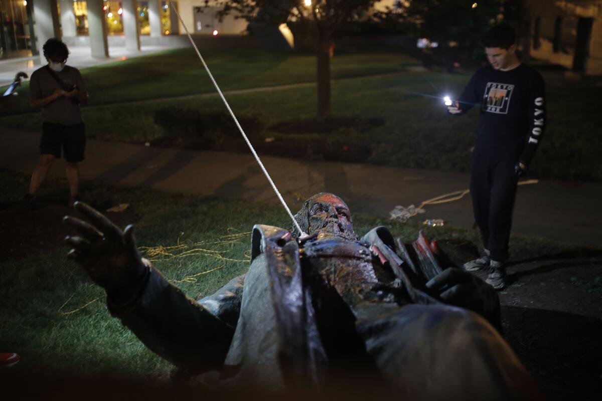 People film the statue of a Confederate general, Albert Pike, after it was toppled by protesters and set afire in Washington.