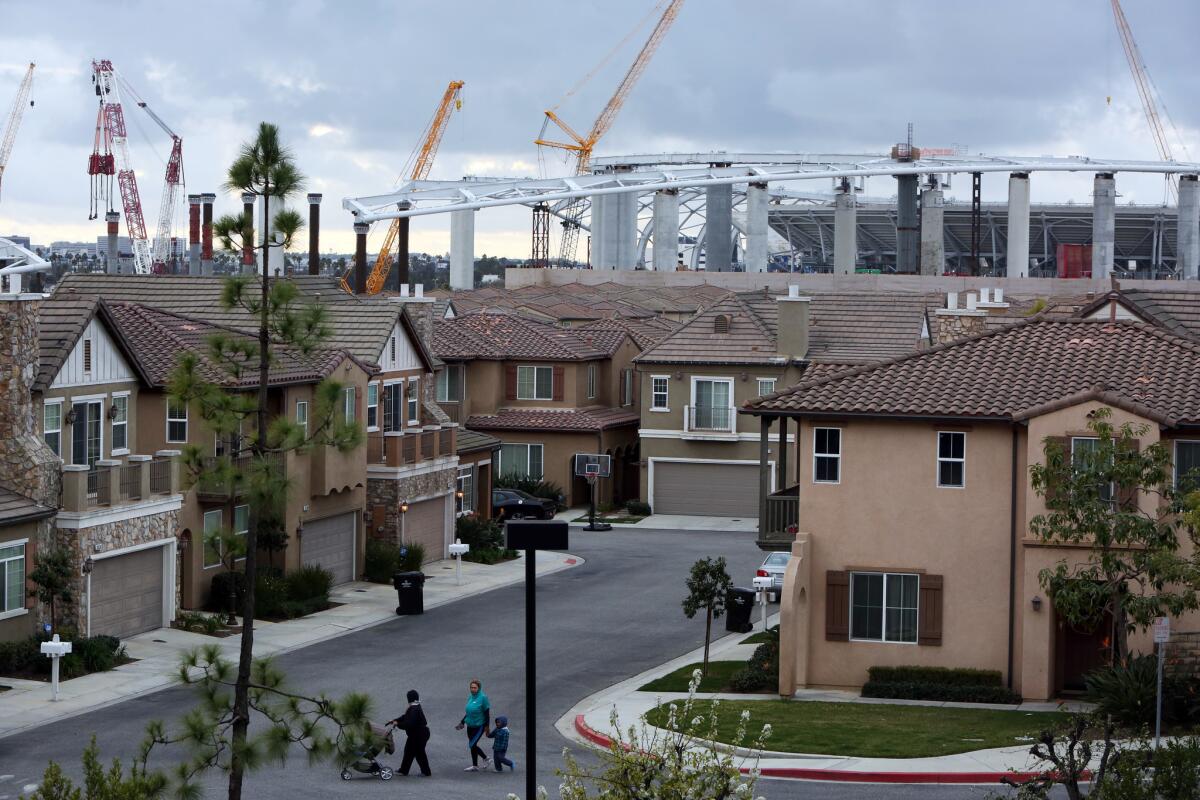 The rising stadium complex looms behind the gated community of Renaissance Homes in Inglewood.