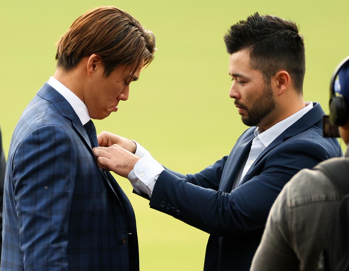 Yoshinobu Yamamoto has his tie fixed before a news conference in the center field plaza at Dodger Stadium.