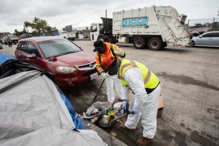 San Diego, CA - May 25: Stanley Morris (left) and Terrence Crosby (right), sanitation workers with the city's Hot Spot clean-up team, pick up trash along an overpass near 17th Street in San Diego, CA on Thursday, May 25, 2023. The team travels around different downtown locations looking for places that need to be cleaned up. (Adriana Heldiz / The San Diego Union-Tribune)
