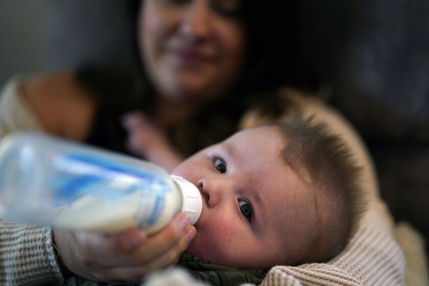 Ashley Maddox feeds her 5-month-old son, Cole, with formula she bought through a Facebook group of mothers in need Thursday, May 12, 2022, in Imperial Beach, Calif. "I connected with a gal in my group and she had seven cans of the formula I need that were just sitting in her house that her baby didn't need anymore," she said. "So I drove out, it was about a 20-minute drive and picked it up and paid her. It was a miracle." (AP Photo/Gregory Bull)