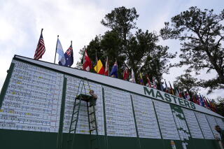 Scores are posted by hand on the main leaderboard at the Masters golf tournament.