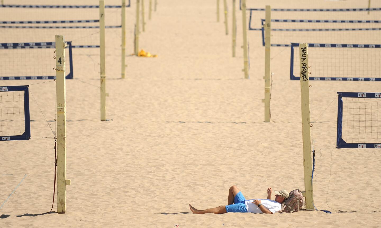 Frank Kaiser of Lawndale relaxes in the shade as he watches a volleyball game in Manhattan Beach on a hot summer day.