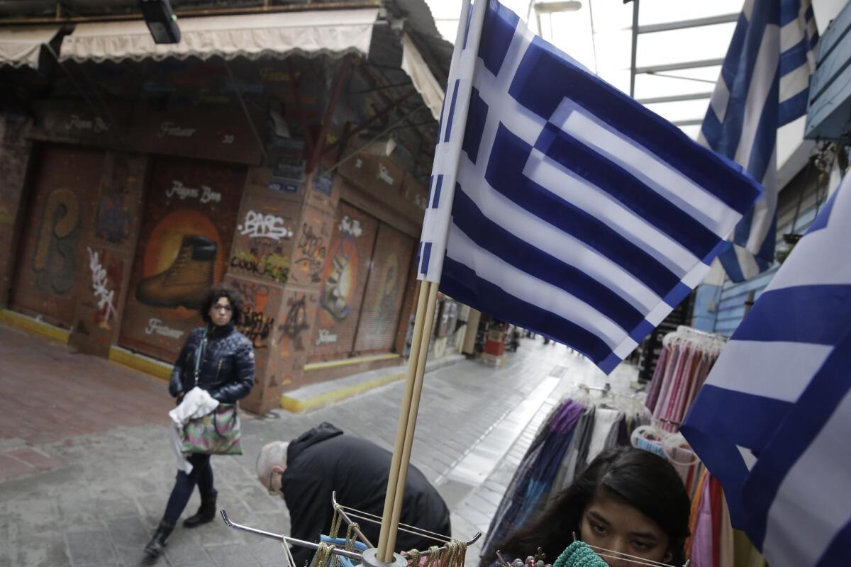 Greek flags fly as a tourist walks by a souvenir shop in Athens on March 9.