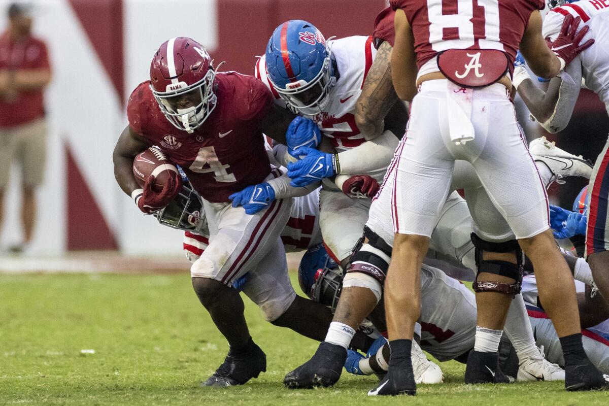 Alabama running back Brian Robinson Jr. (4) breaks through the Mississippi line with Mississippi defensive lineman Tariqious Tisdale (22) holding on to him during the second half of an NCAA college football game, Saturday, Oct. 2, 2021, in Tuscaloosa, Ala. (AP Photo/Vasha Hunt)