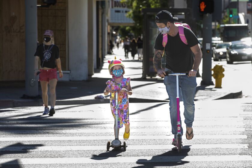 LOS ANGELES, CA-JUNE 8, 2020: People (didn't want to give their names) wear protective masks against the coronavirus while riding scooters, as they cross the intersection of Laurel Canyon Blvd. and Ventura Blvd. in Studio City. (Mel Melcon/Los Angeles Times)