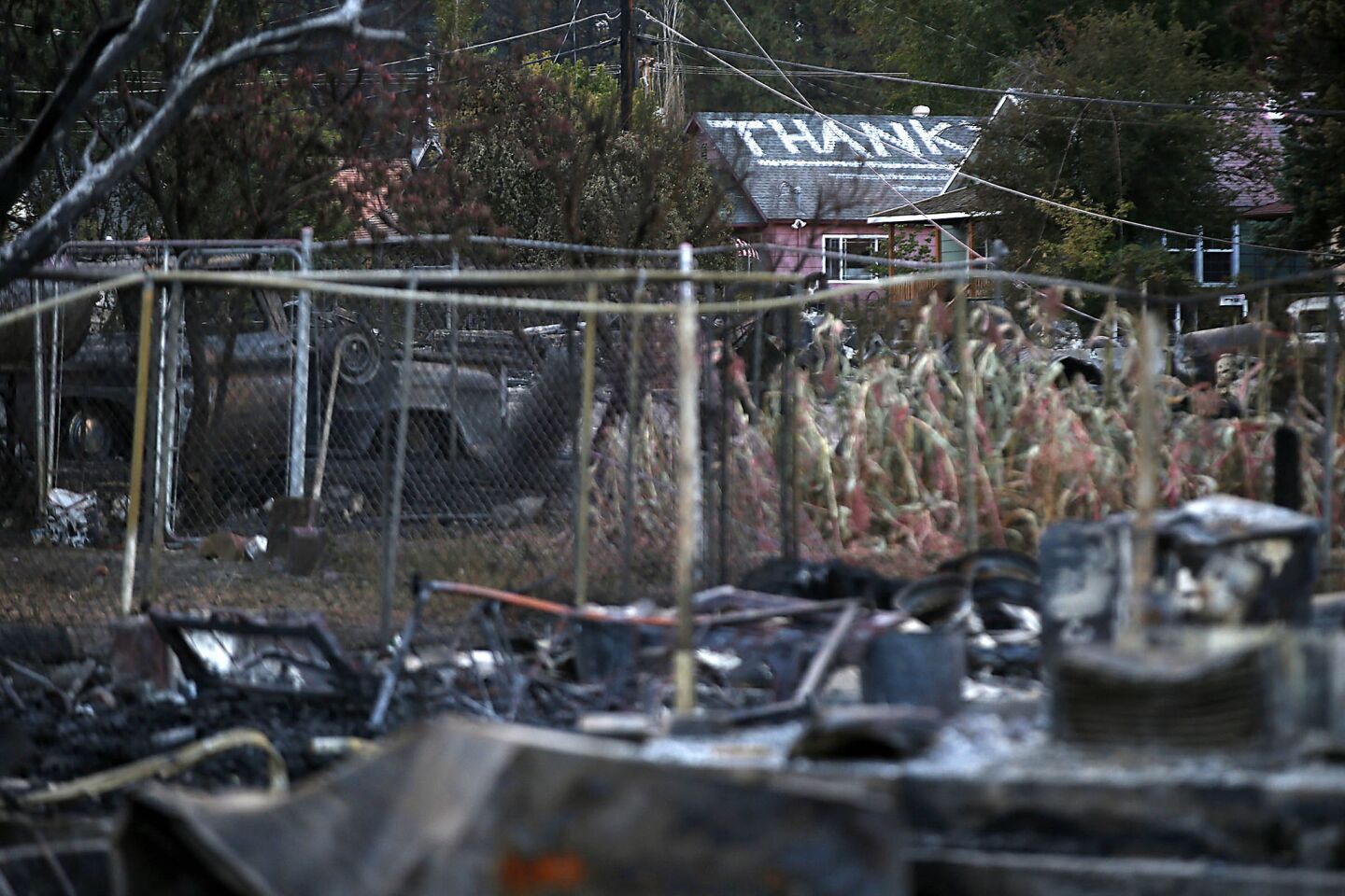 A sign of thanks painted on the rooftop of a home spared by the Boles fire can be seen from nearby lots of smoldering debris in Weed, Calif.