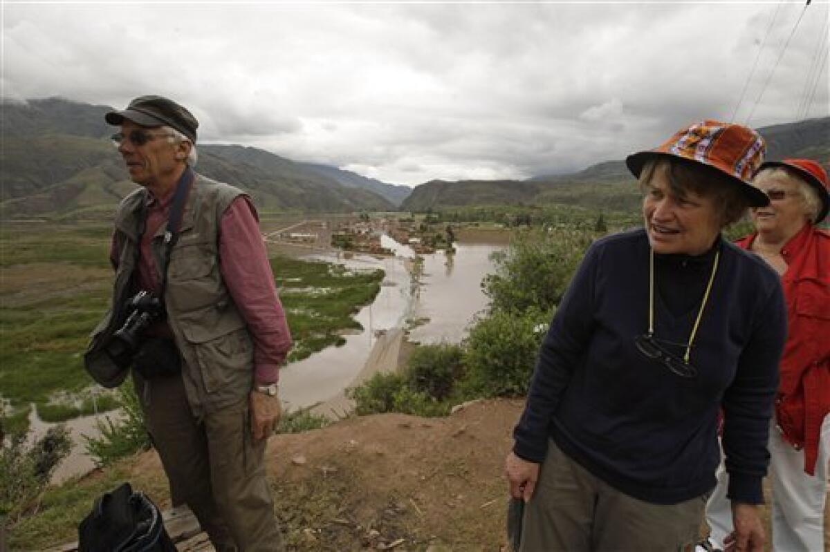 Swedish tourists Kjell-Eric Persson, left, and Holgersson Ingemar, second from right, observe a flooded area after the Huatanay river overflowed in Cuzco, Peru, Wednesday, Jan. 27, 2010. Heavy rains and mudslides in Peru have blocked the train route to the ancient Inca citadel of Macchu Picchu, leaving nearly 2,000 tourists stranded. Woman at far right is unidentified.(AP Photo/Martin Mejia)
