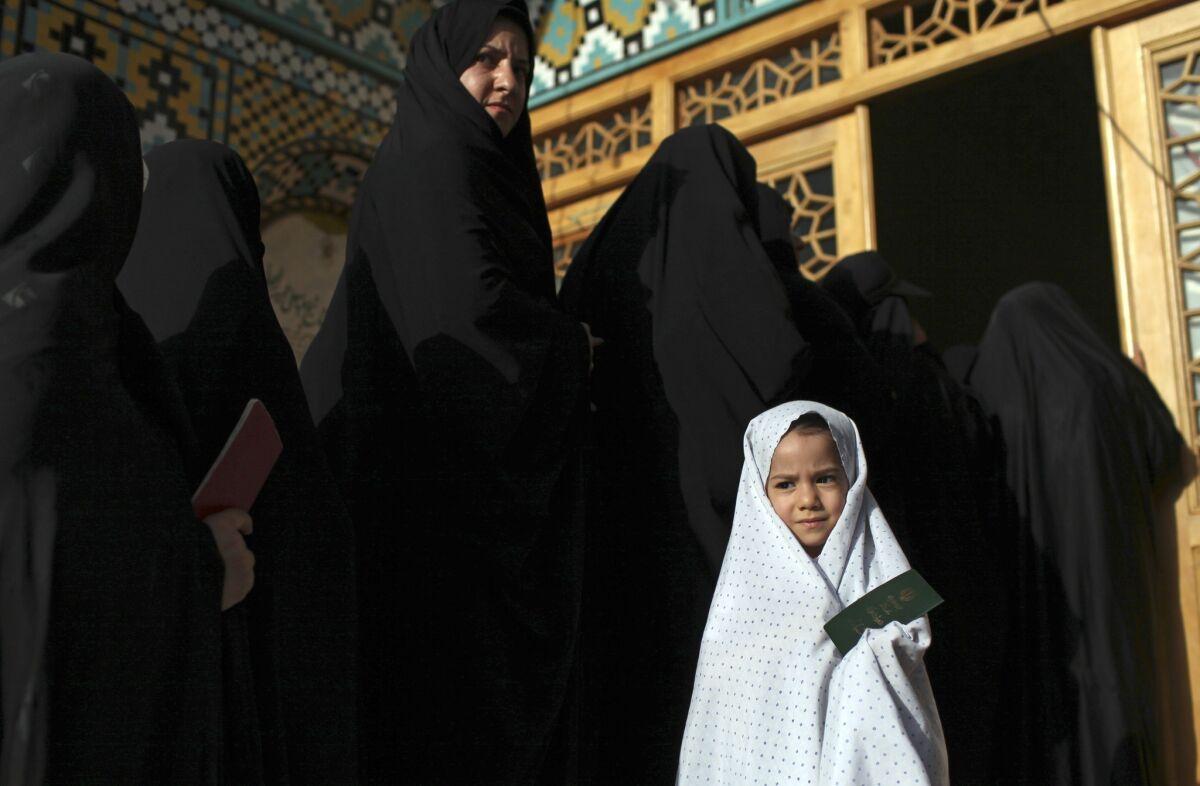 Iranian women line up to vote in Qom last summer. Conservatives in Tehran are calling for stricter enforcement of Islamic dress codes for women.
