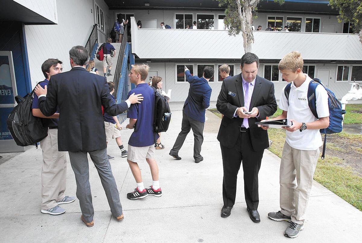 Head of School David O'Neil, left, and languages teacher Mike Arldt, right, help students navigate on the first day of school at Pacifica Christian High School in Newport Beach on Tuesday morning.