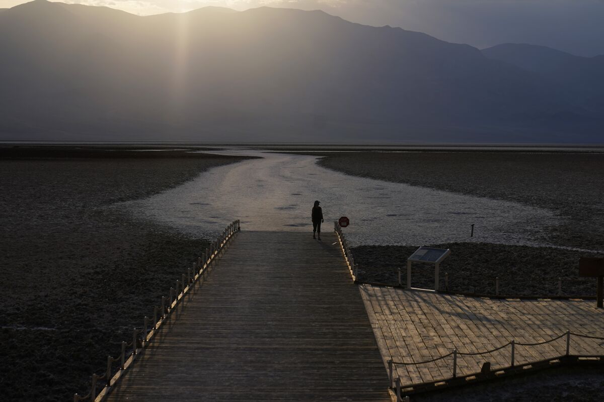 A person walks on a boardwalk at the Badwater Basin salt flats in Death Valley National Park.