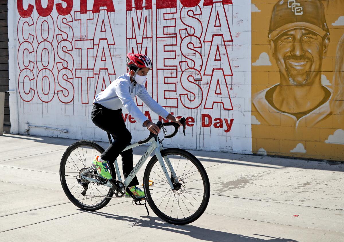 A boy wearing a face mask tries out a new bicycle from the Specialized Bicycles store in Costa Mesa on Saturday.