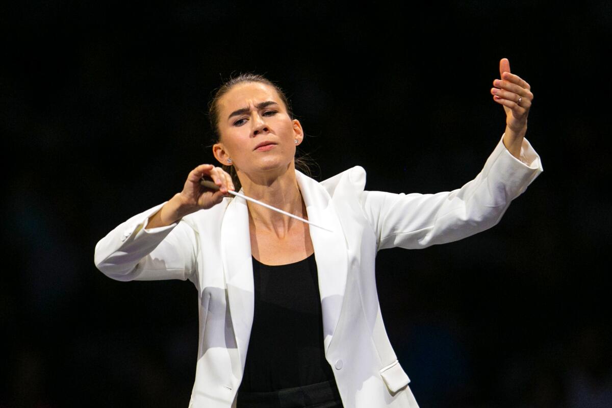 A woman wearing a white blazer holds a baton