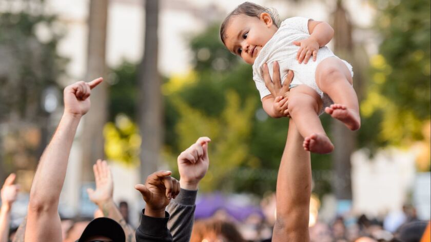 A baby is raised in the air by parent during Oxnard singer Anderson .Paak's .Paak House in the Park event on Dec. 8, 2018, at MacArthur Park in Los Angeles.