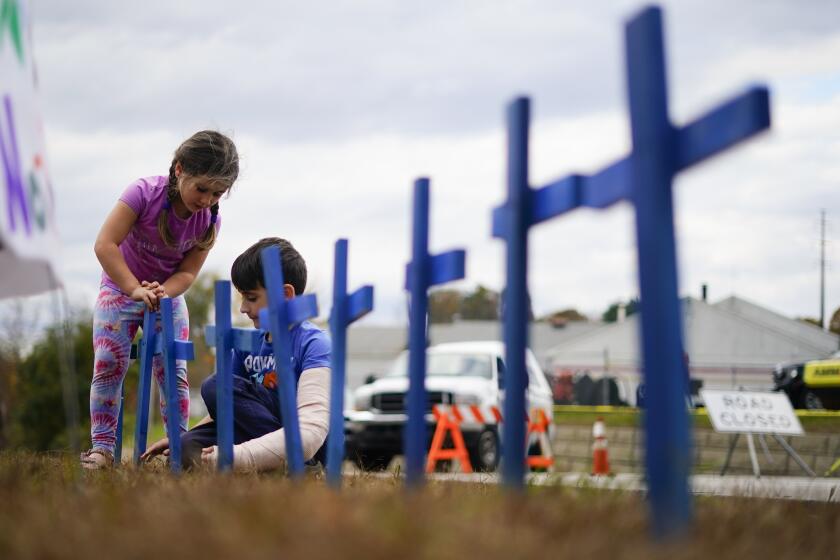 Lucy Allard, 5, and her brother Zeke Allard, 8, plant crosses in honor of the victims of this week's mass shooting in Lewiston, Maine, Saturday, Oct. 28, 2023. The residents of Lewiston are embarking on a path to healing after a man suspected of killing several people earlier this week was found dead. (AP Photo/Matt Rourke)