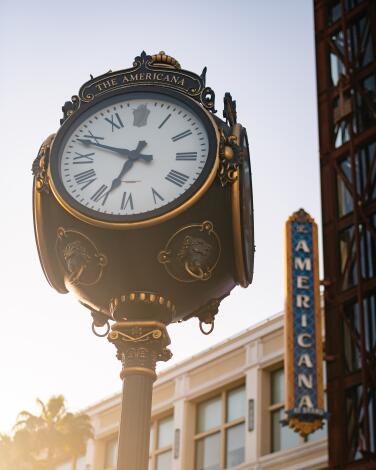 The clock tower at the Americana at Brand in Glendale, with the theater-style sign in the background.