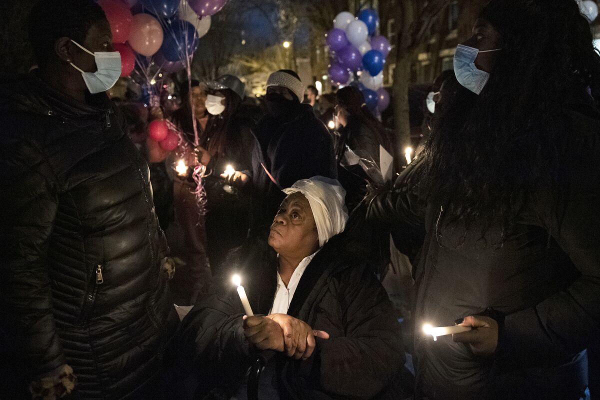 A family member gathers with community members for a candlelight vigil, Thursday evening, Jan. 6, 2022, to remember those who perished in a rowhouse fire in Philadelphia. (Joe Lamberti/Camden Courier-Post via AP)