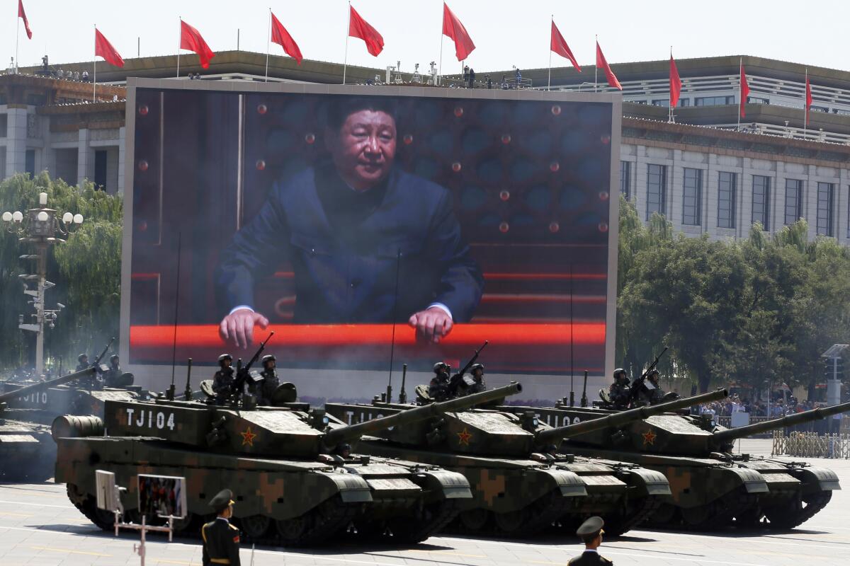 In 2015 Chinese President Xi Jinping is displayed on a screen as Chinese battle tanks take part in a parade in Beijing. 