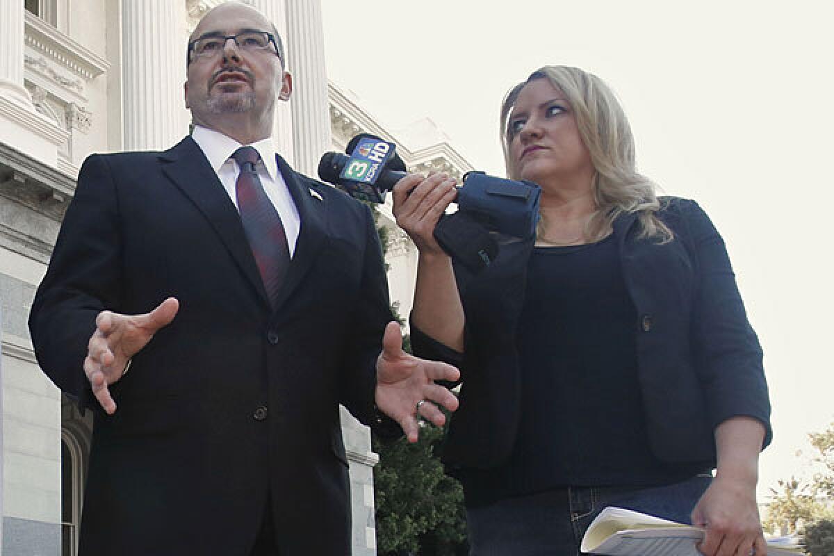 Jennifer Kerns holds microphones for Assemblyman Tim Donnelly (R-Twin Peaks) last October in Sacramento.