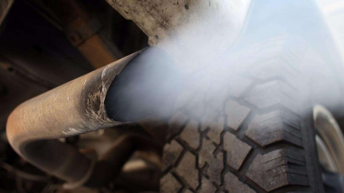 Exhaust flows out of the tailpipe of a vehicle at a muffler repair shop.