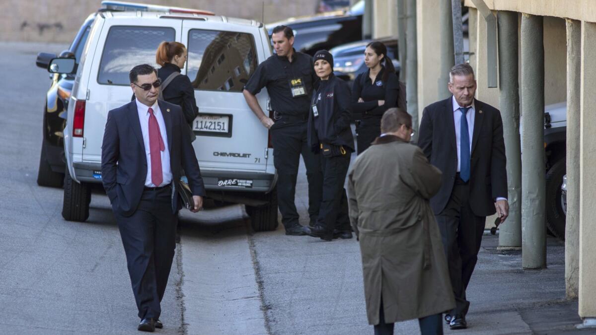 Investigators crowd a carport area at an apartment building in Van Nuys, where a woman in her 40s and a 13-year-old boy were found dead Wednesday.