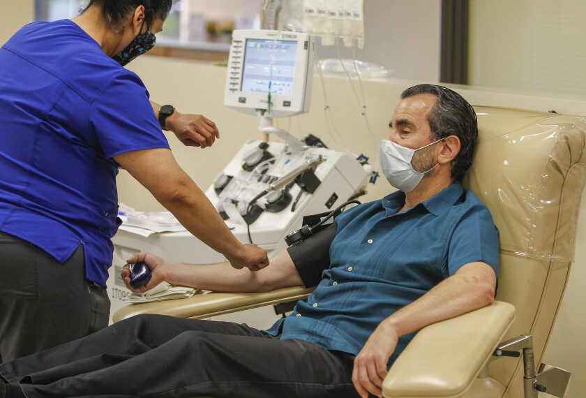Dan Galant (right) makes his plasma donation with donor technician Leya Ramos (left) at the San Diego Blood Bank on Wednesday in San Diego. His plasma will be used to treat COVID-19 patients.