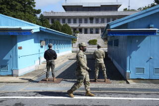 People in military fatigues are seen standing between two blue buildings