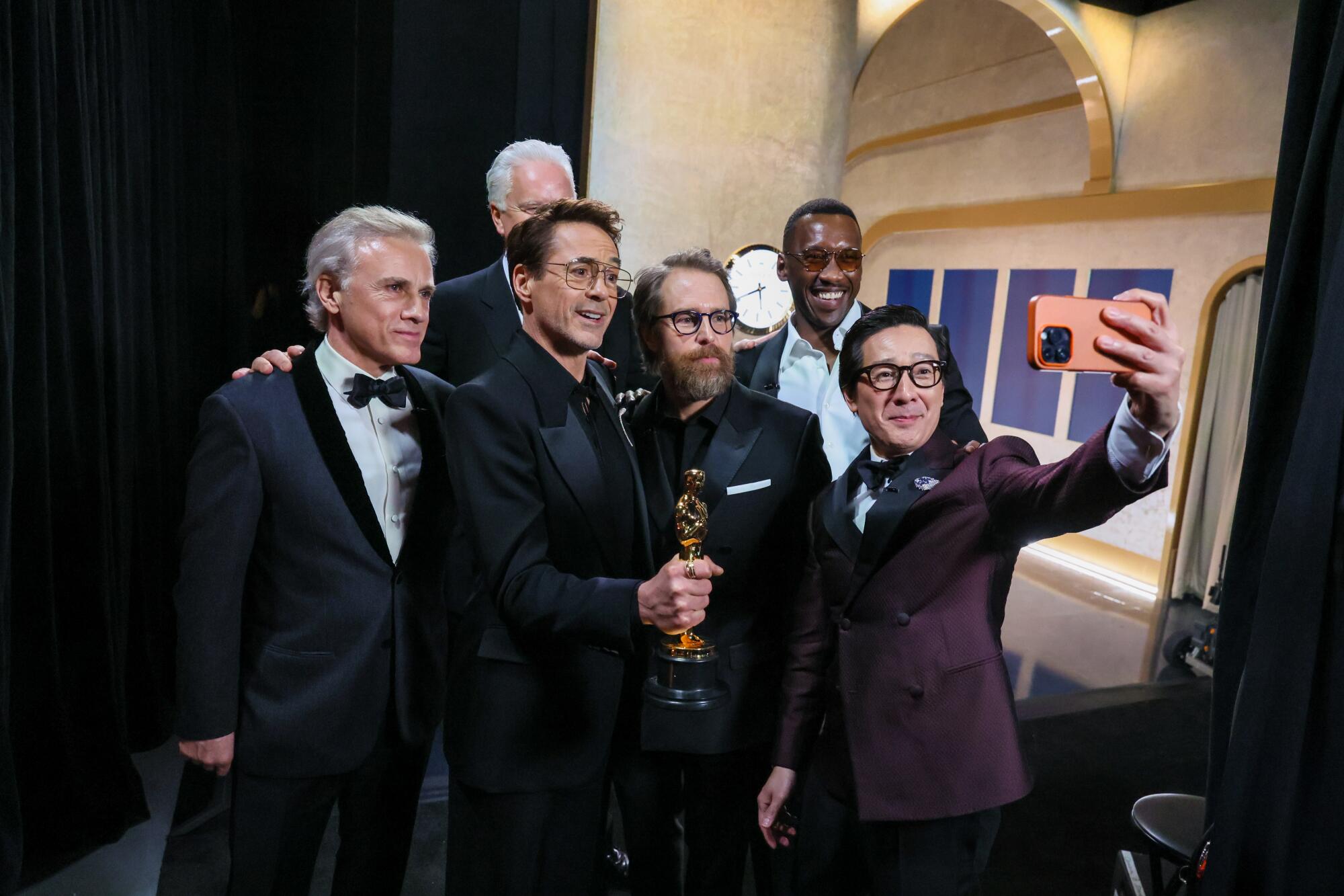 Le gagnant de l'acteur de soutien Robert Downey, Jr. entouré de présentateurs dans les coulisses lors de la 96e cérémonie annuelle des Oscars.