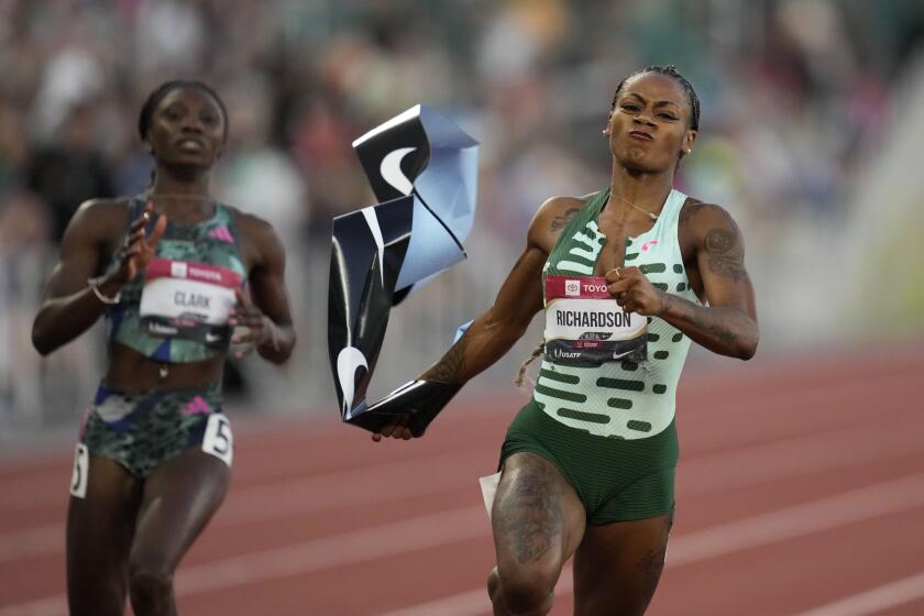 Sha'Carri Richardson grabs the tape as she wins the women's 100 meter finals ahead of Tamara Clark during the U.S. track and field championships in Eugene, Ore., Friday, July 7, 2023. (AP Photo/Ashley Landis)