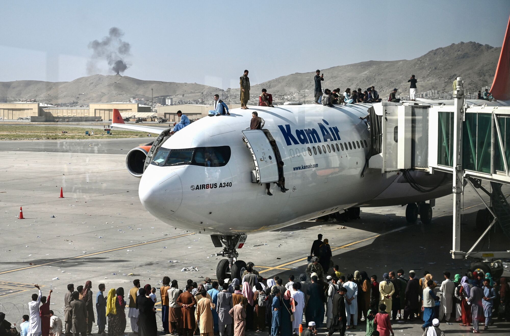 People climb atop a plane at the international airport in Kabul.